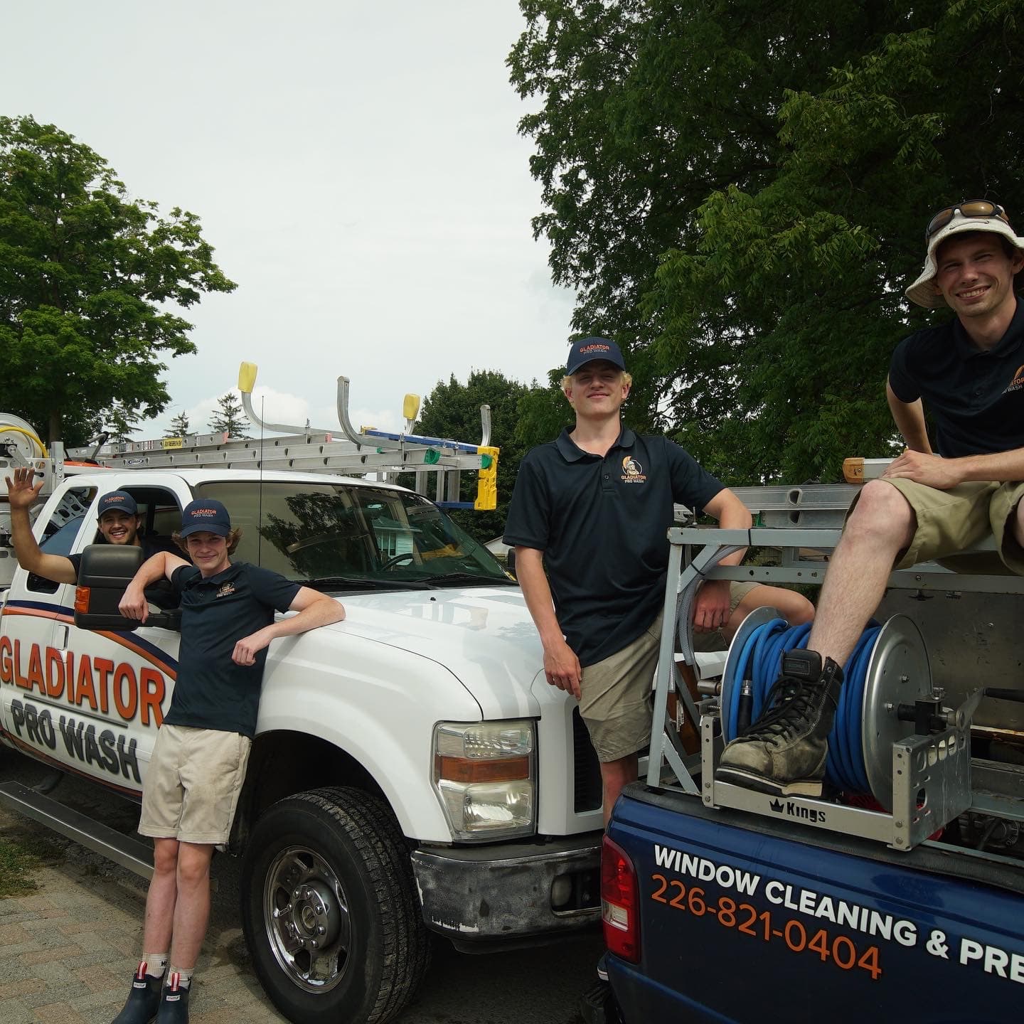 Four young Gladiator Pro Wash technicians smiling on and around a branded work truck
