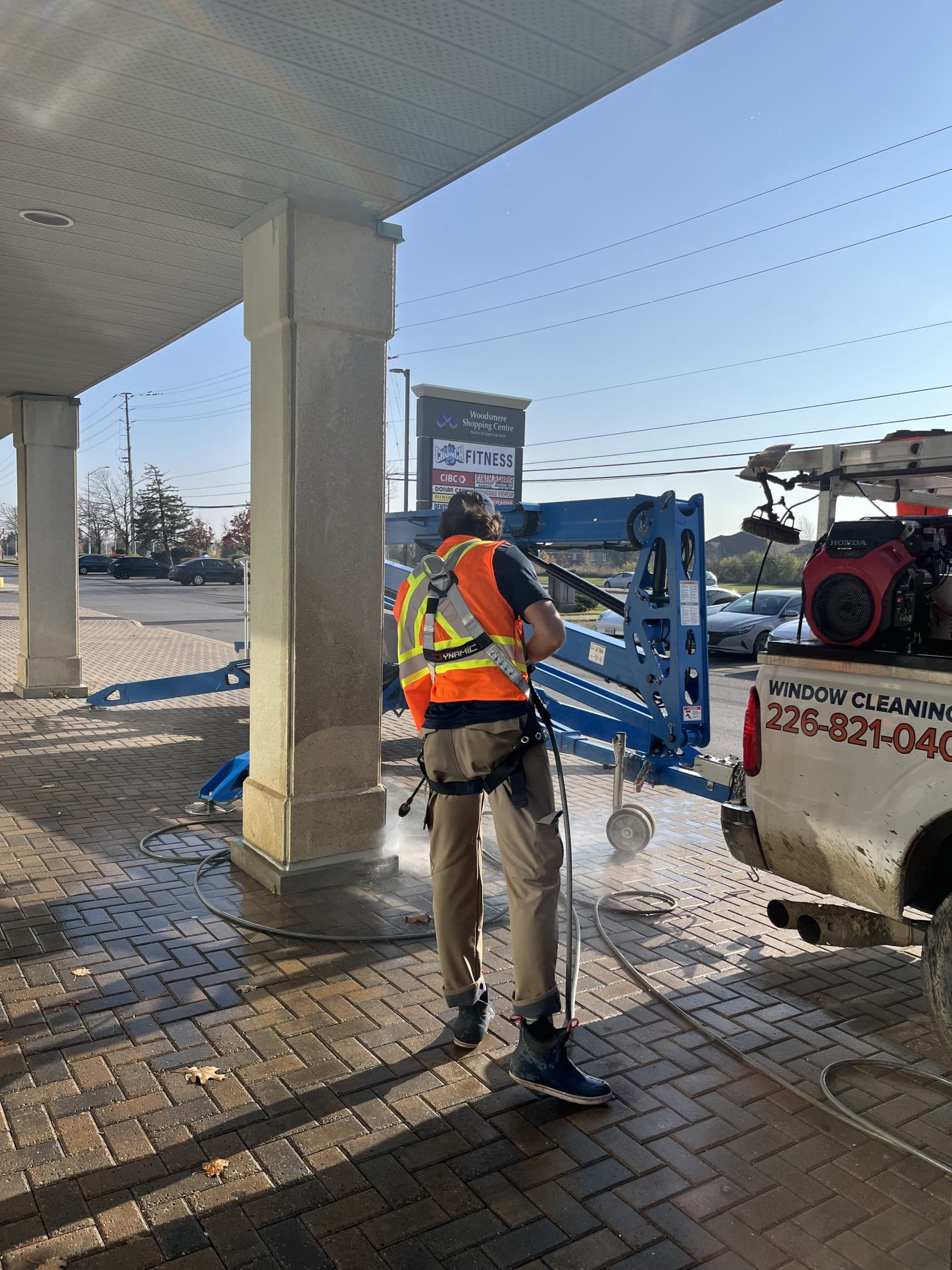 A technician with a ladder washing a commercial spa storefront and awning