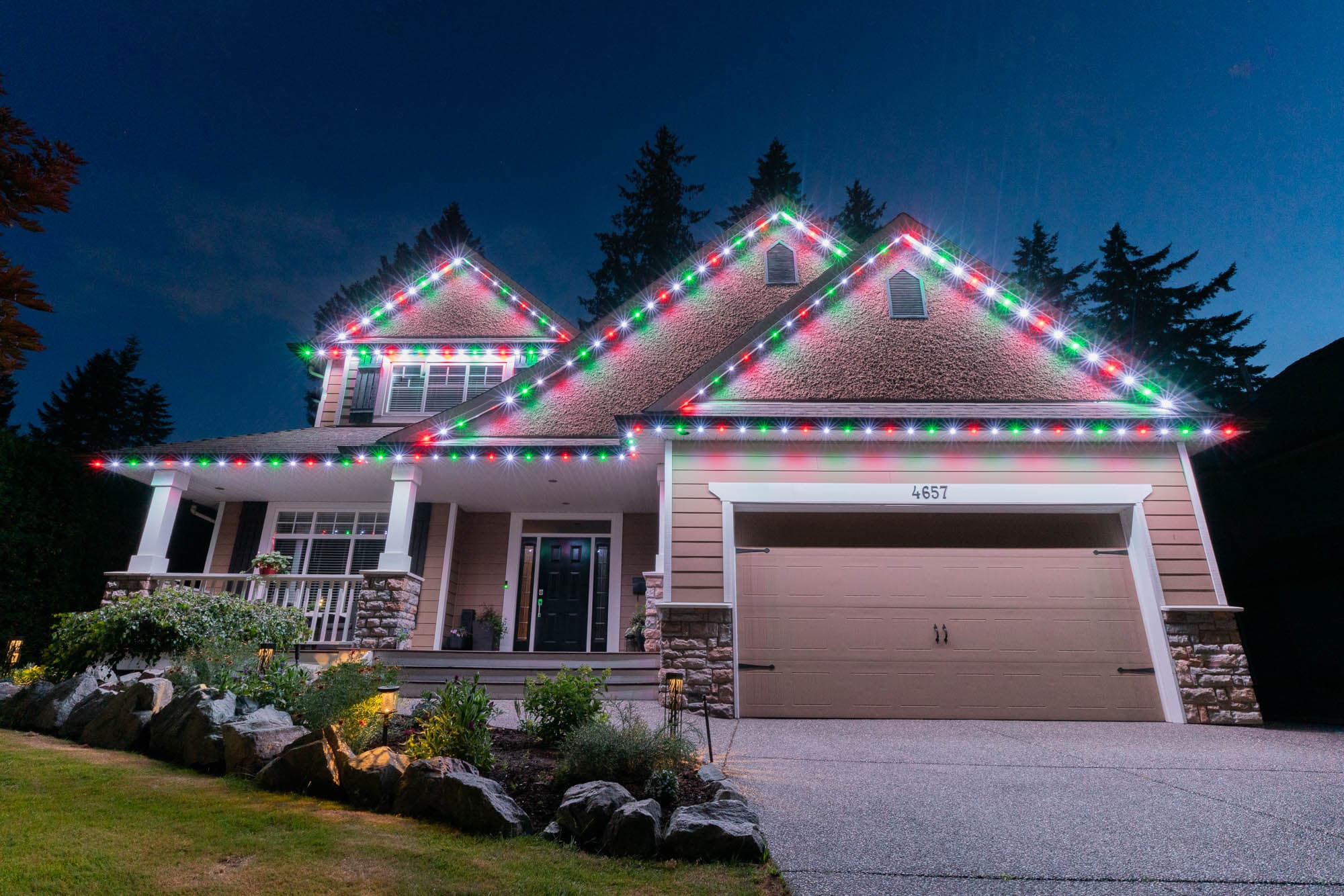 A home at night with permanent red and green architectural lighting on every roofline